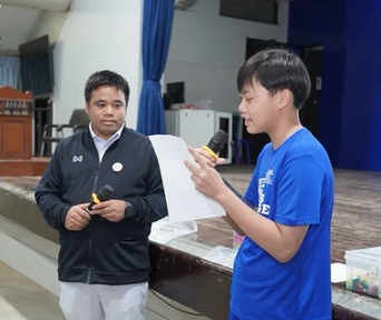 Natthaphat speaking into a microphone during a school activity